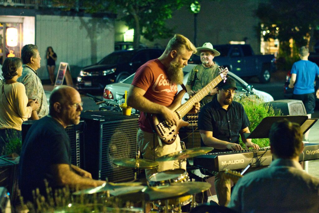 A vibrant street band performing live music at night, entertaining a small crowd outdoors.