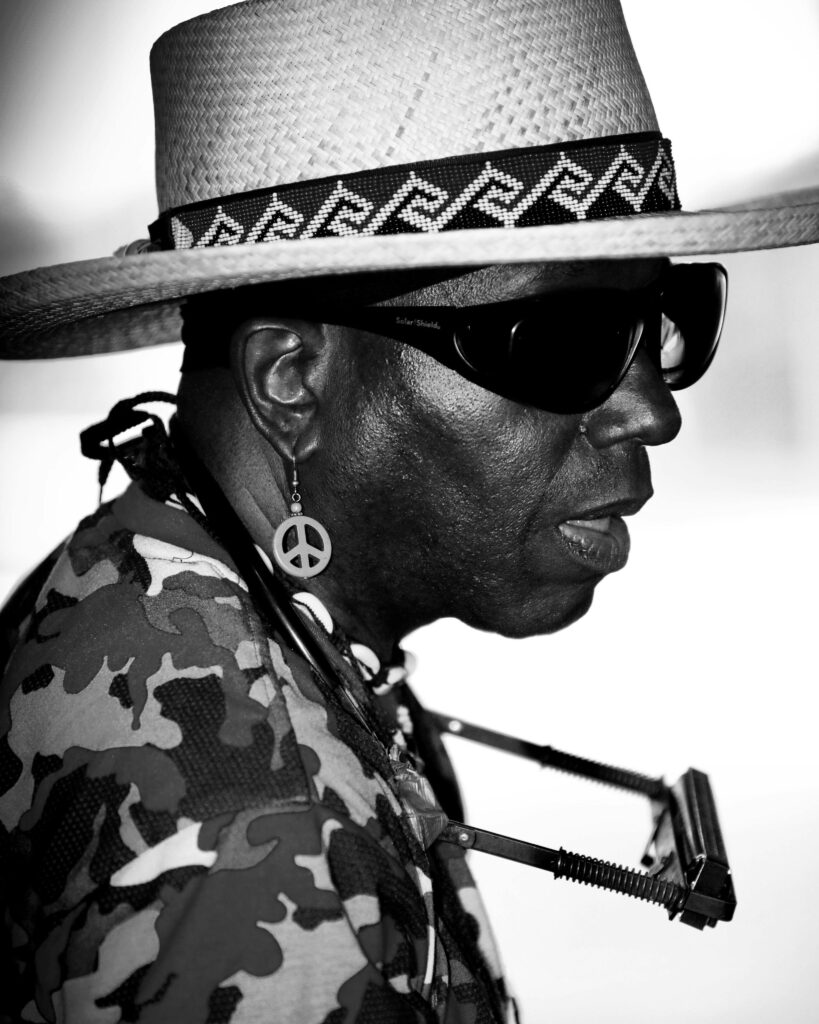 Stylish African man in straw hat and sunglasses, playing harmonica.