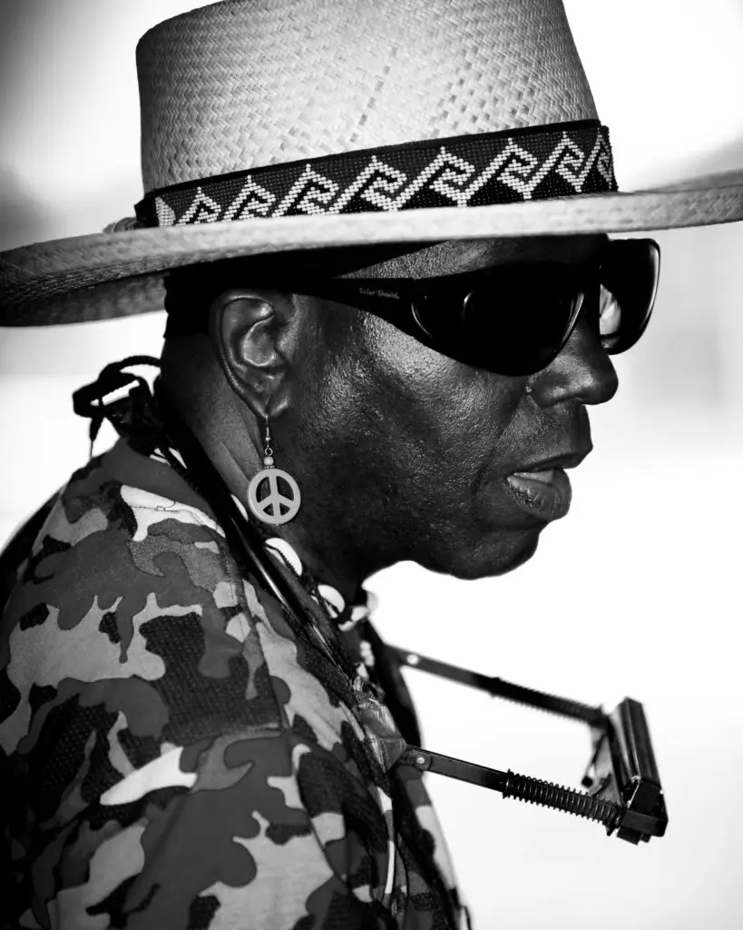 Stylish African man in straw hat and sunglasses, playing harmonica.