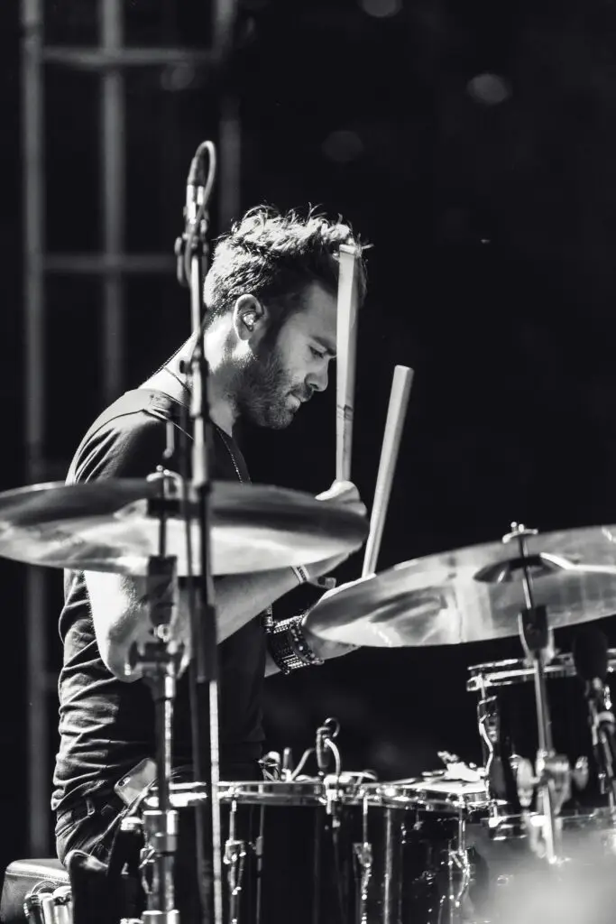 Black and white photo of a drummer performing passionately during a live music concert.