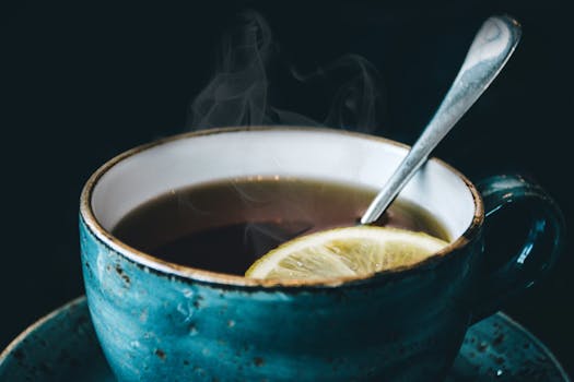 Close-up of aromatic steaming lemon herbal tea served in a ceramic cup with saucer.